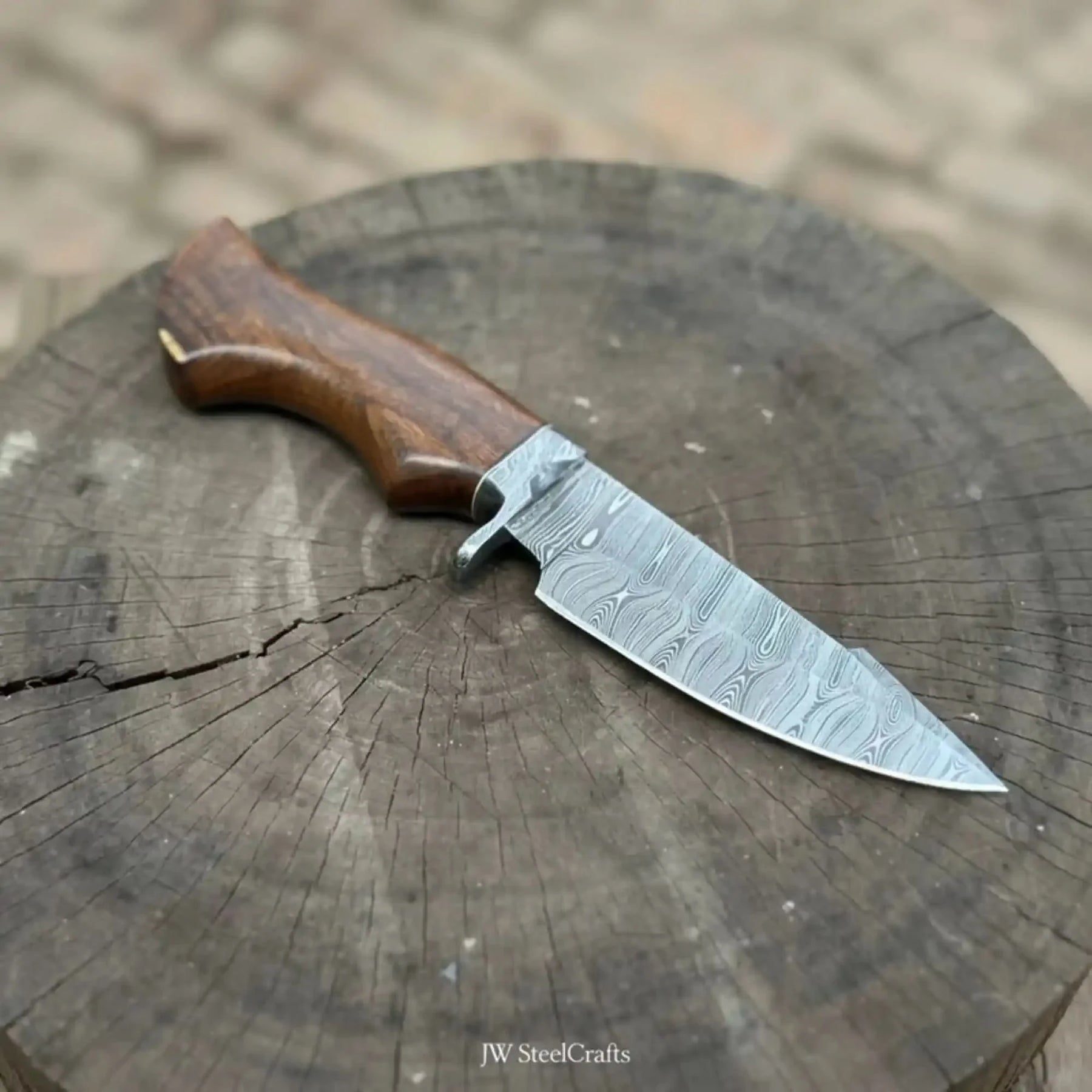 Handmade damascus steel knife with wood handle on dark surface