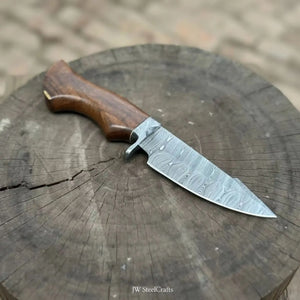 Handmade damascus steel knife with wood handle on dark surface