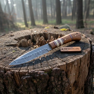 Handmade damascus steel knife with wood handle on dark surface