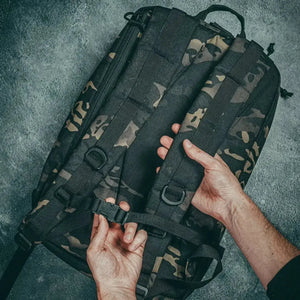 Hands adjusting buckle strap on black camouflage 24 Hour backpack