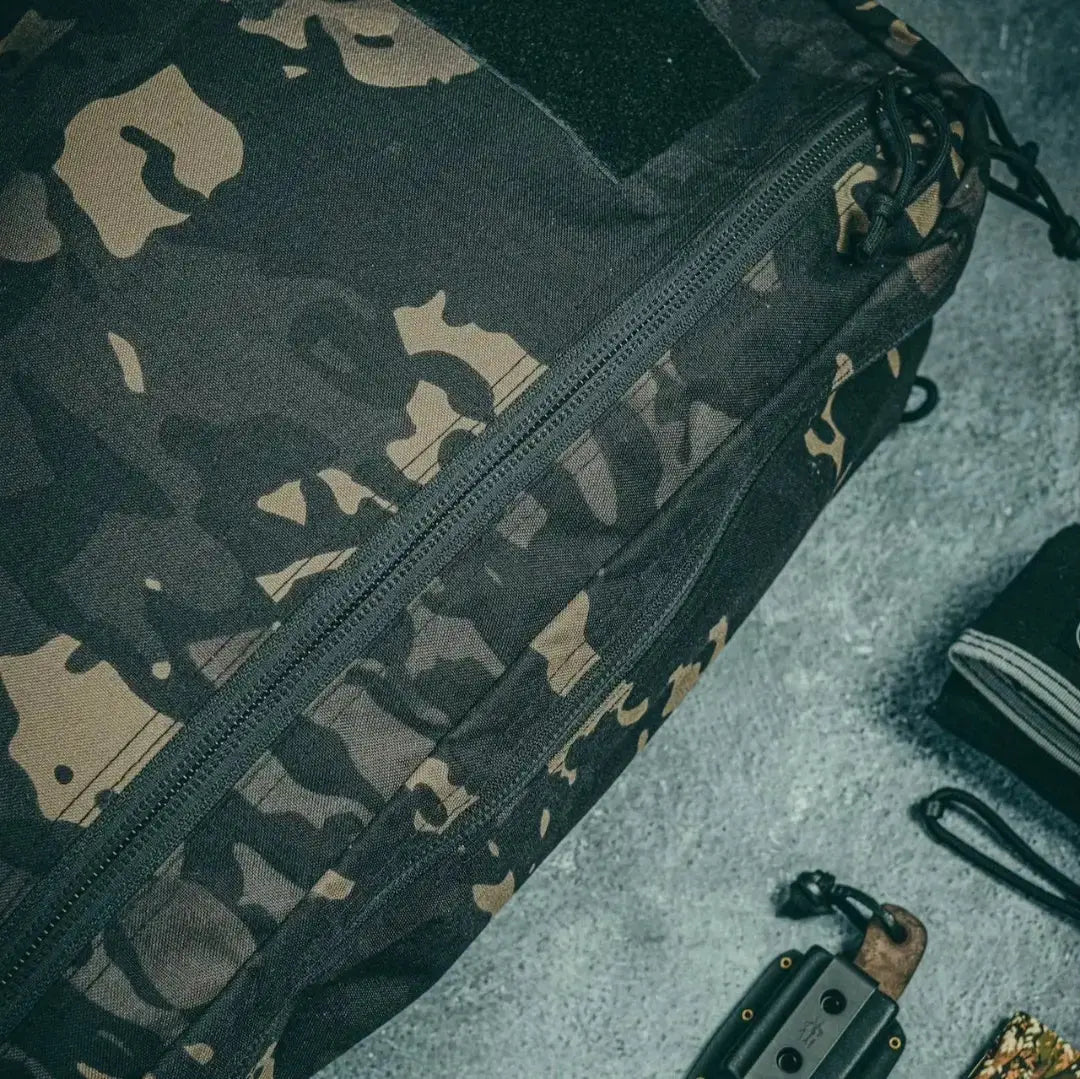 Close-up of a black and tan camo backpack with a prominent zipper.