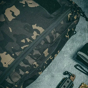 Close-up of a black and tan camo backpack with a prominent zipper.