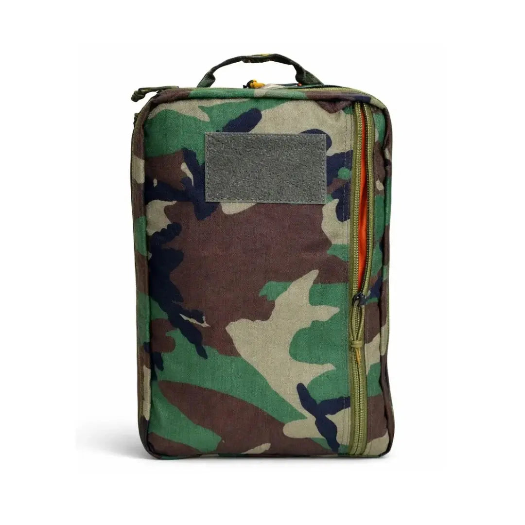 Camouflage backpack with a grey patch panel and zippered opening showing an orange interior.