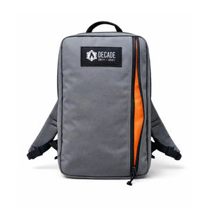 Gray backpack with an orange zipper opening and a black logo patch.