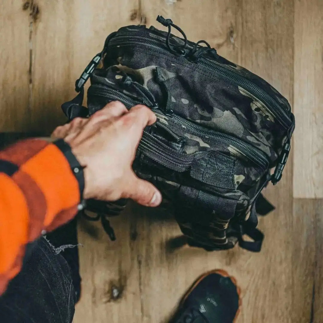 Camouflage backpack with multiple zippered compartments and adjustable straps.