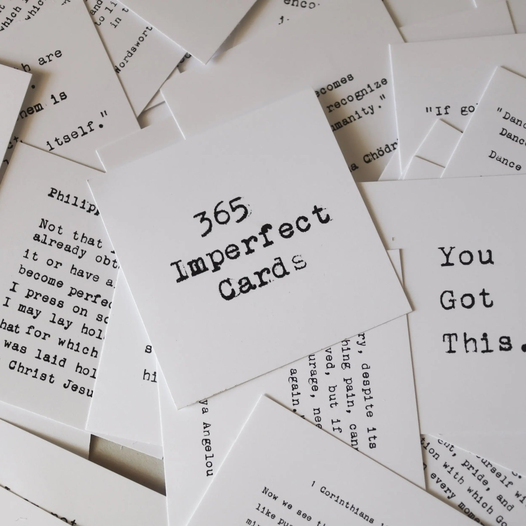 Pile of white cards with black typewriter text, featuring "365 Imperfect Cards".