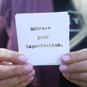 Hands holding a card with text "Embrace your imperfection."