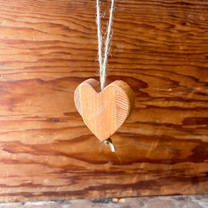 Wooden heart ornament with natural jute twine hanging against a wooden background.