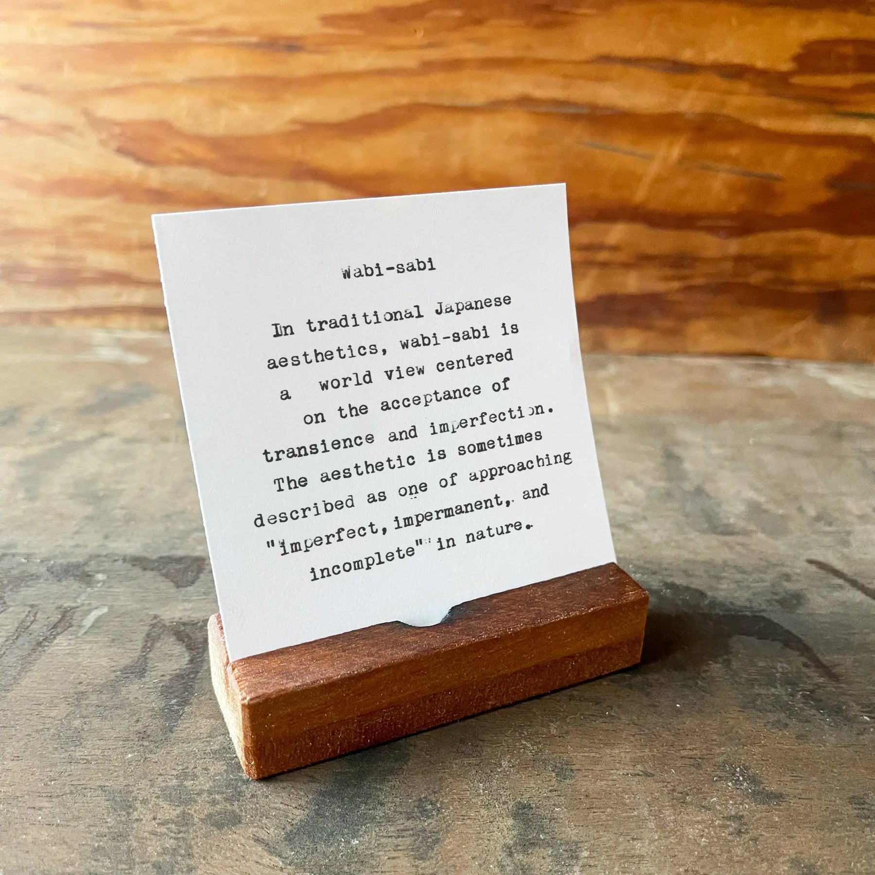 Wabi-sabi quote on a card in a reclaimed wood desk stand.
