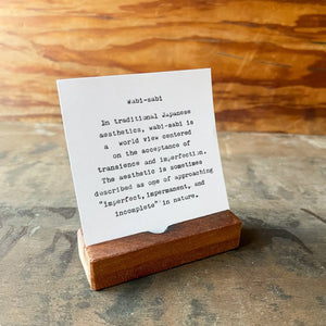 Wabi-sabi quote on a card in a reclaimed wood desk stand.