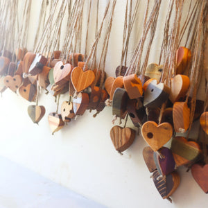 Wooden heart ornaments with jute twine hanging against a white wall.