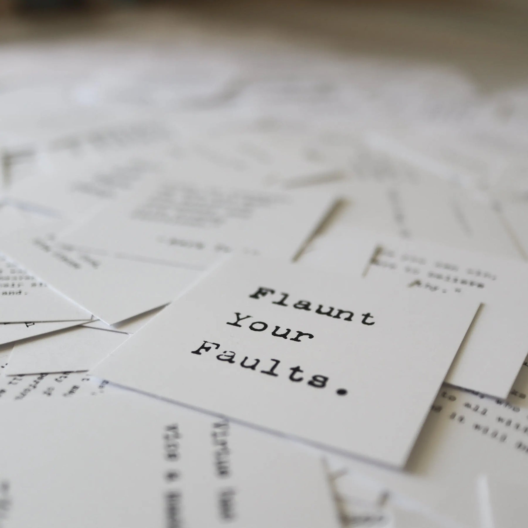 Card with "Flaunt Your Faults" in typewriter font among scattered papers.