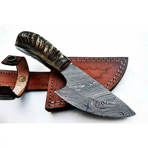 Handmade damascus steel knife with horn handle on dark surface