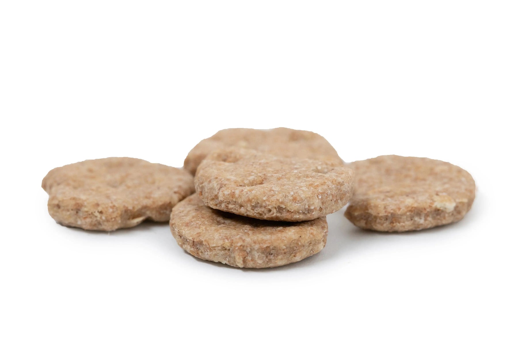 Several round, crunchy peanut butter dog biscuits piled together.