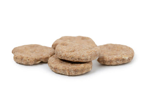Several round, crunchy peanut butter dog biscuits piled together.