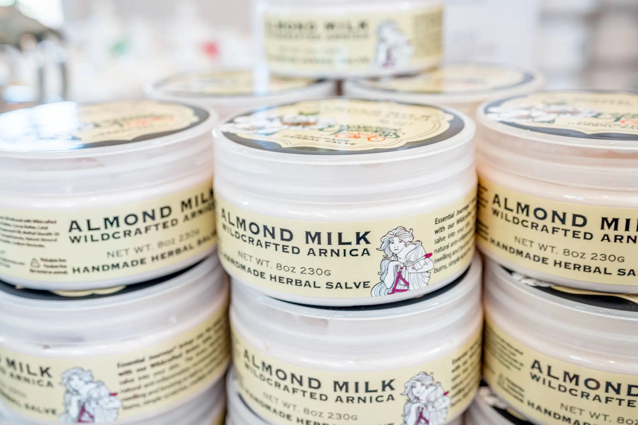Stacked jars of Almond Milk Arnica herbal salve with visible labeling.