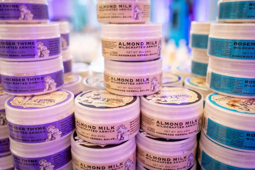 Almond Milk Wildcrafted Arnica Herbal Salve jars with purple and yellow labels.