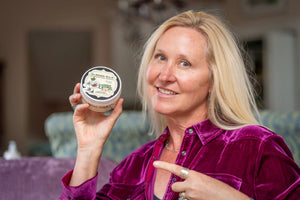 Woman holding Essential Journeys Almond Milk Arnica Salve.