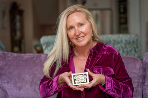 Woman holding a bar of Almond Milk soap with floral design.