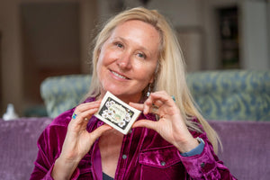 Woman holding a bar of Almond Milk Soap with floral packaging.