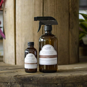 Amber glass bottle of Still Magnolia All Purpose Cleaner in Cinnamon Cedarwood Delight scent.