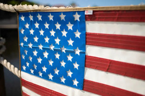 American flag made from red, white, and blue rubber fire hose with cut-out stars.