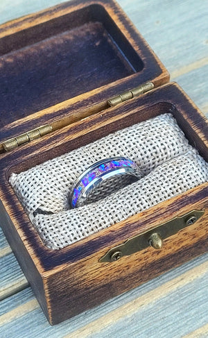 Amethyst opal ring inside a rustic wooden box with metal hinges and a burlap lining.