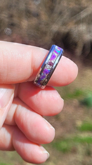 Hand holding a ring with a purple and silver amethyst opal and cremation ash inlay.