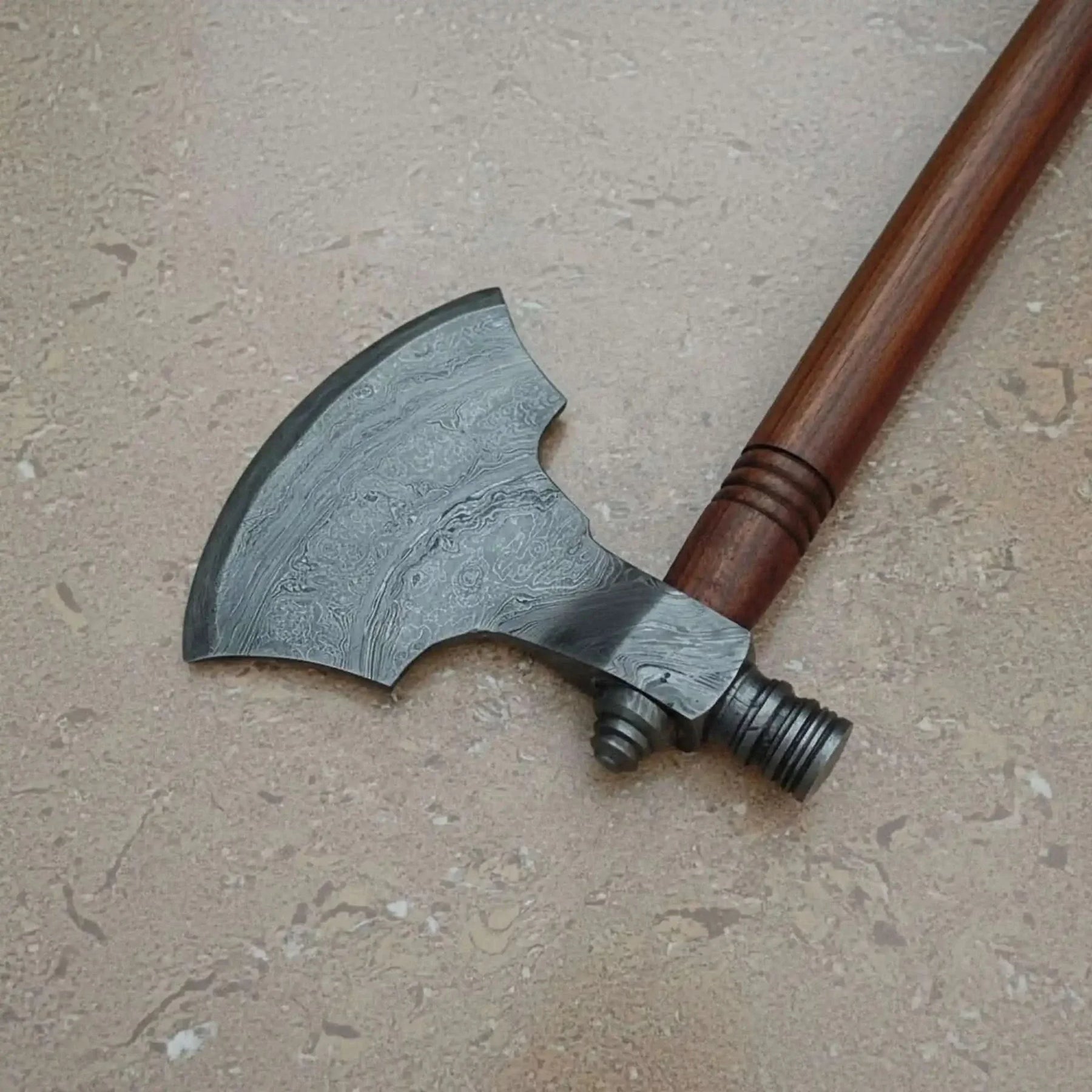 Damascus steel axe head with wood handle on rustic wood surface