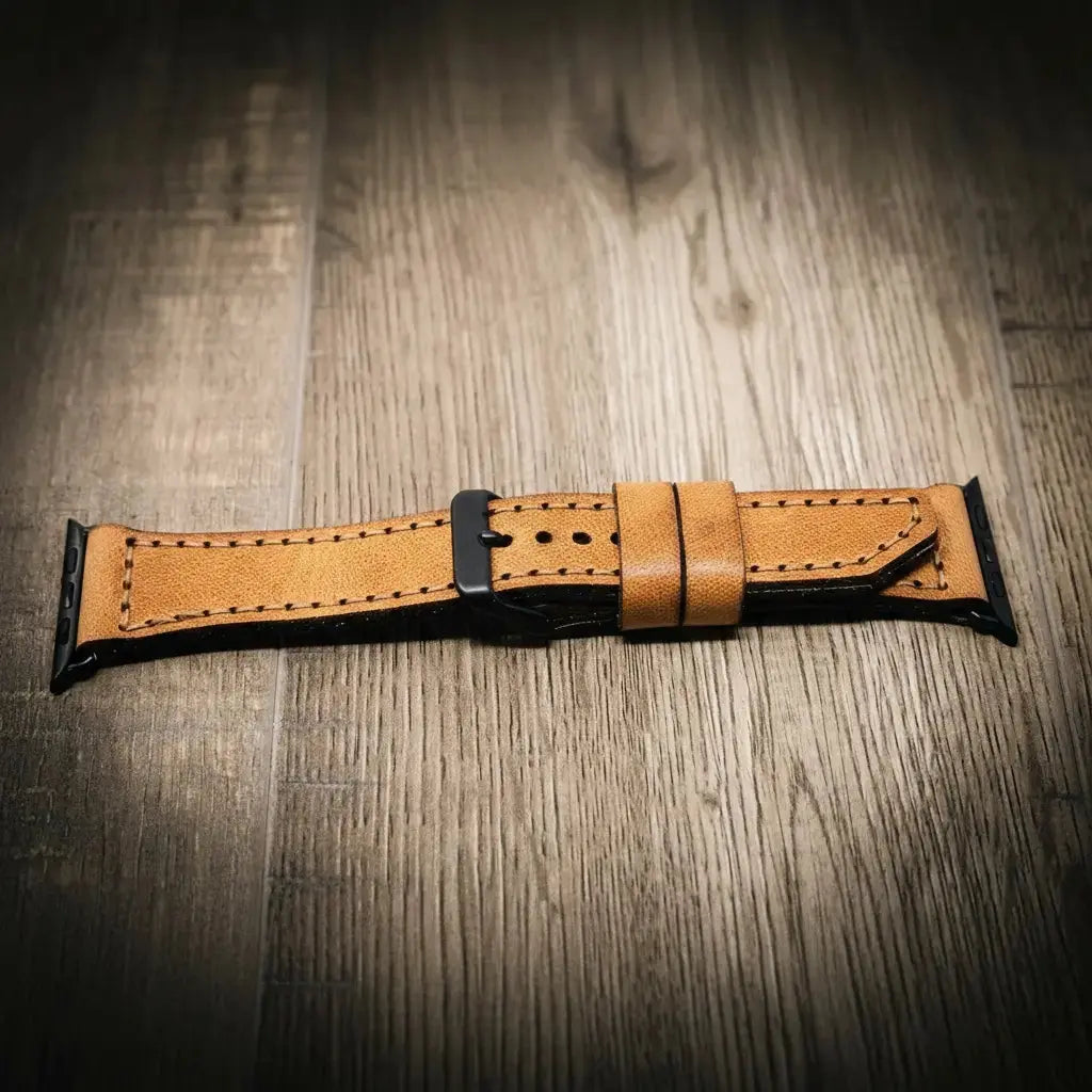 Tan leather Apple Watch band with black buckle and visible stitching.