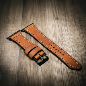 Brown full-grain leather Apple Watch band with black buckle.