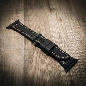 Black leather Apple Watch band with tan stitching and a black buckle.