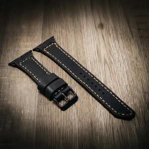 Black leather Apple Watch band with cream stitching and a metal buckle.