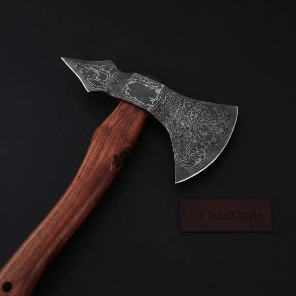 Damascus steel axe head with premium handle on rustic wood surface