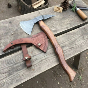 Damascus steel axe head with wood handle on rustic wood surface