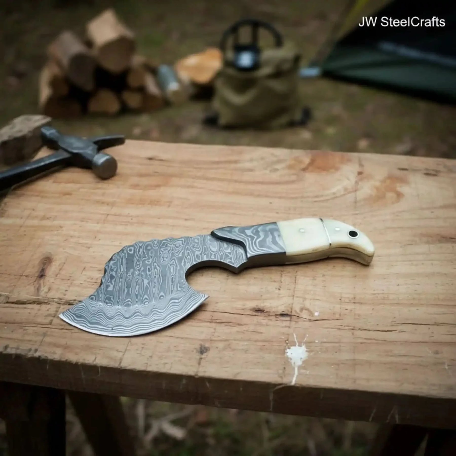 Damascus steel axe head with premium handle on rustic wood surface