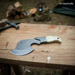 Damascus steel axe head with premium handle on rustic wood surface