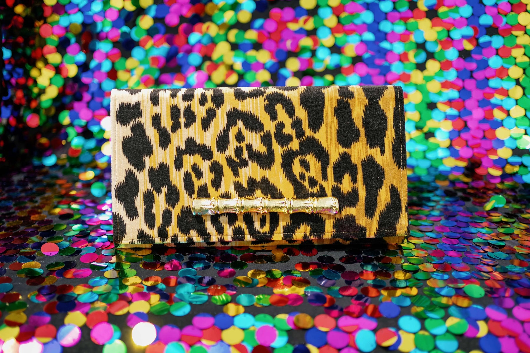 Leopard print velvet clutch with gold bamboo closure on colorful sequins.