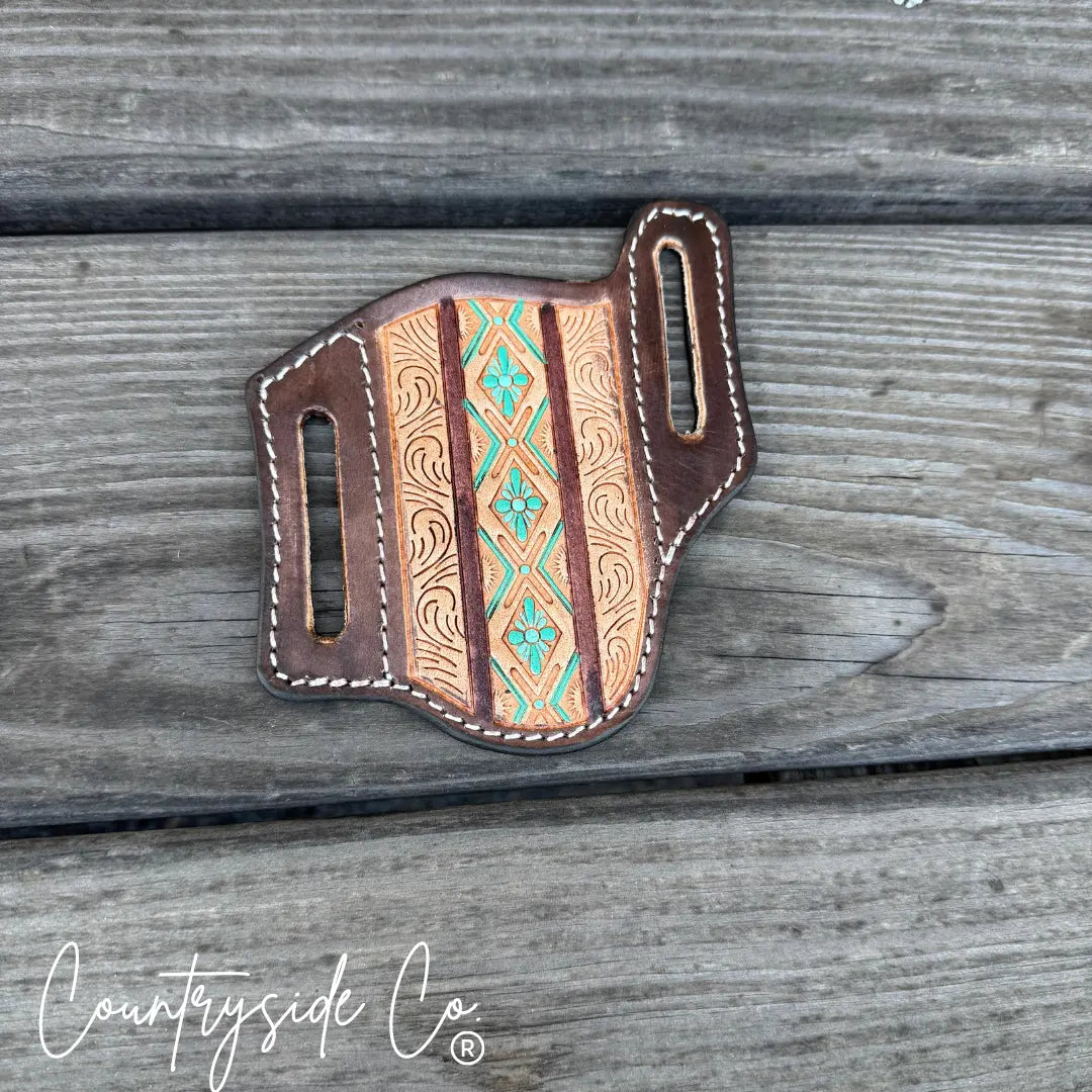 Brown tooled leather knife sheath with Aztec pattern and teal accents.