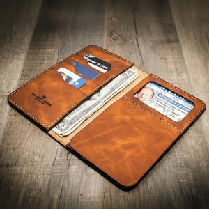 Brown leather long wallet holding cash, cards, and a driver's license.