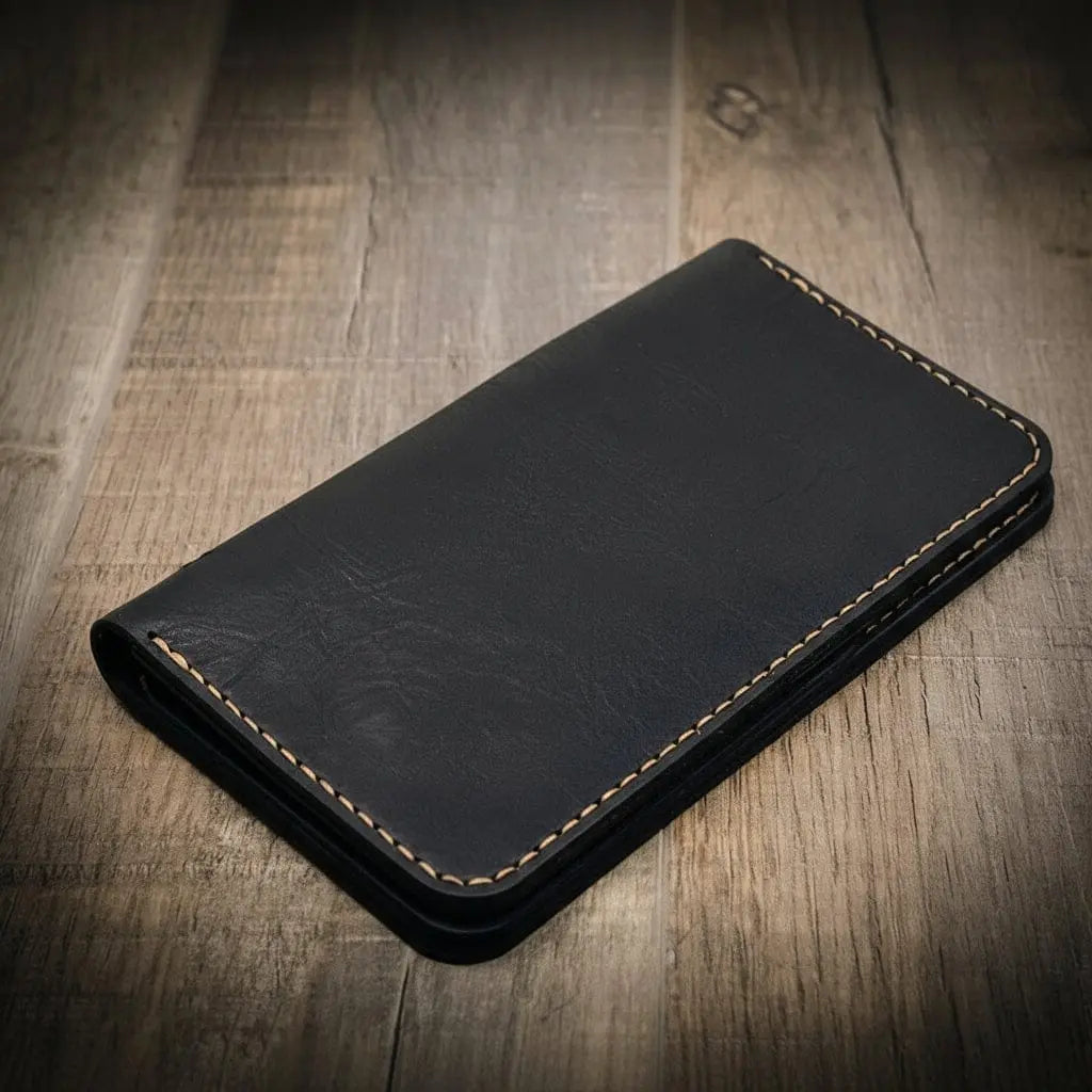 Black leather long wallet with tan contrast stitching on a wooden background.