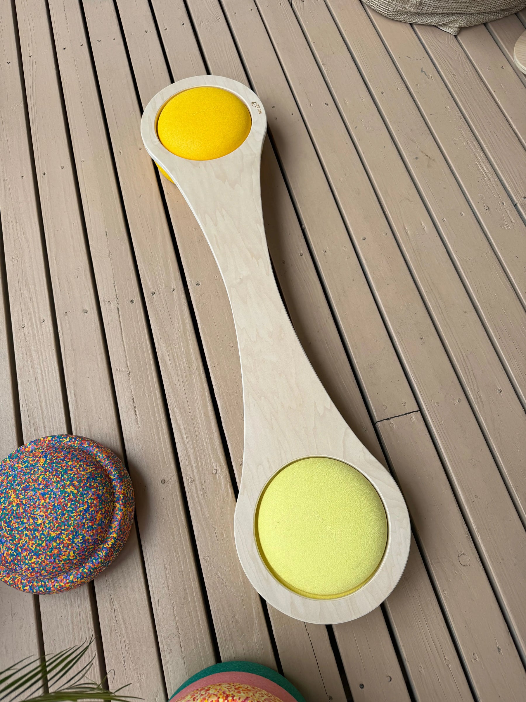 Maple balance board with yellow cushions on a wooden deck