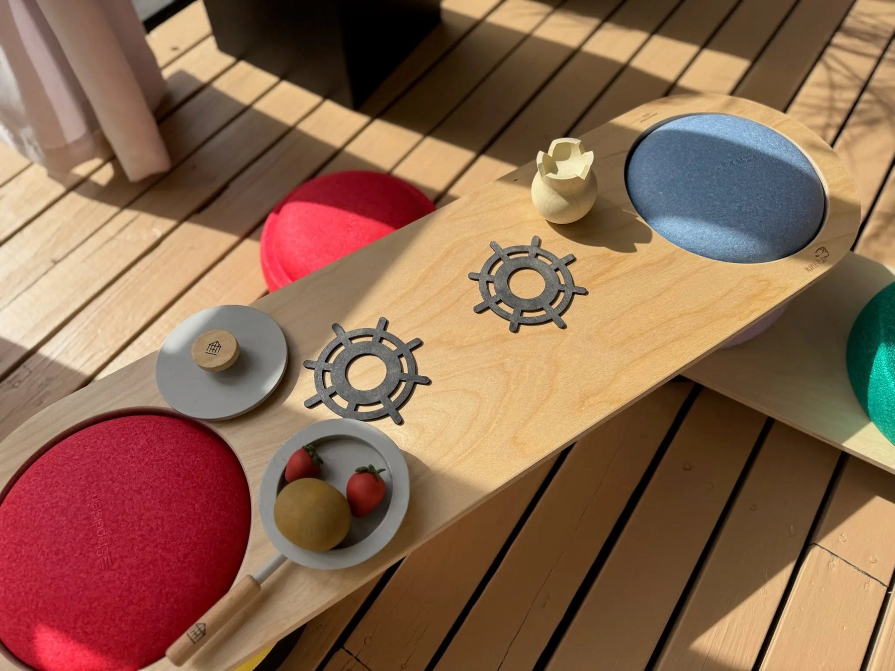 Wooden balance board with red, blue, and green stepping stones for play.