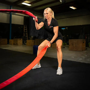 Woman exercising with a red battle rope in a gym
