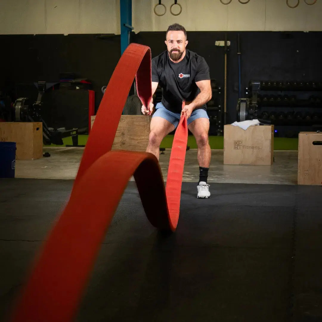 Man using a red battle rope in a gym