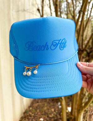 Columbia blue "Beach Hat" trucker hat with pearl detail, held in hand, outdoors.