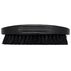 Black beard brush with short bristles and a rounded handle, showing the bristle texture and handle grain.