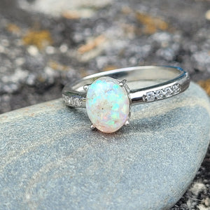 Opal ring in sterling silver with cubic zirconia accents resting on a gray stone.