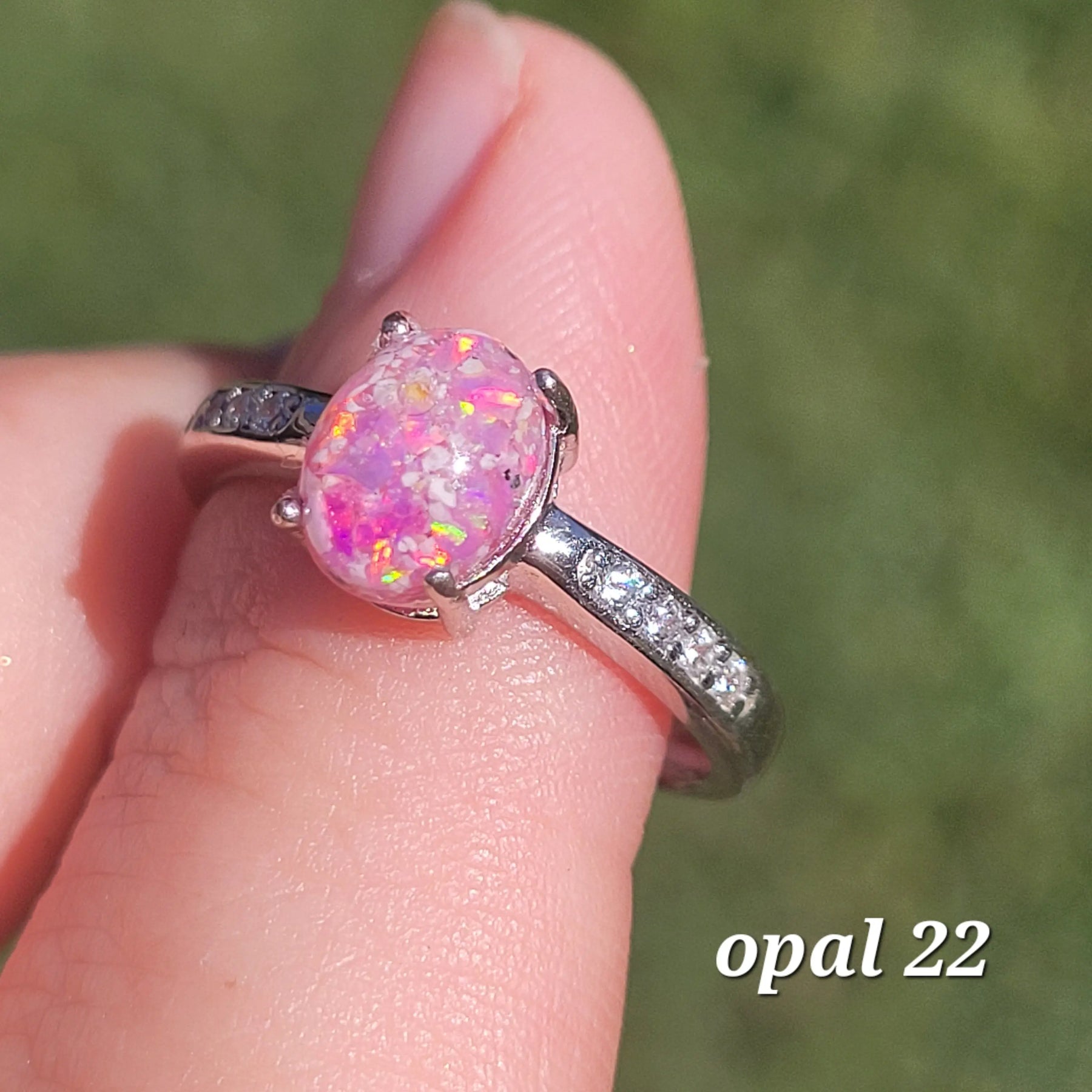 Pink opal ring in silver setting held on a finger, showcasing the stone's color and the ring's design.