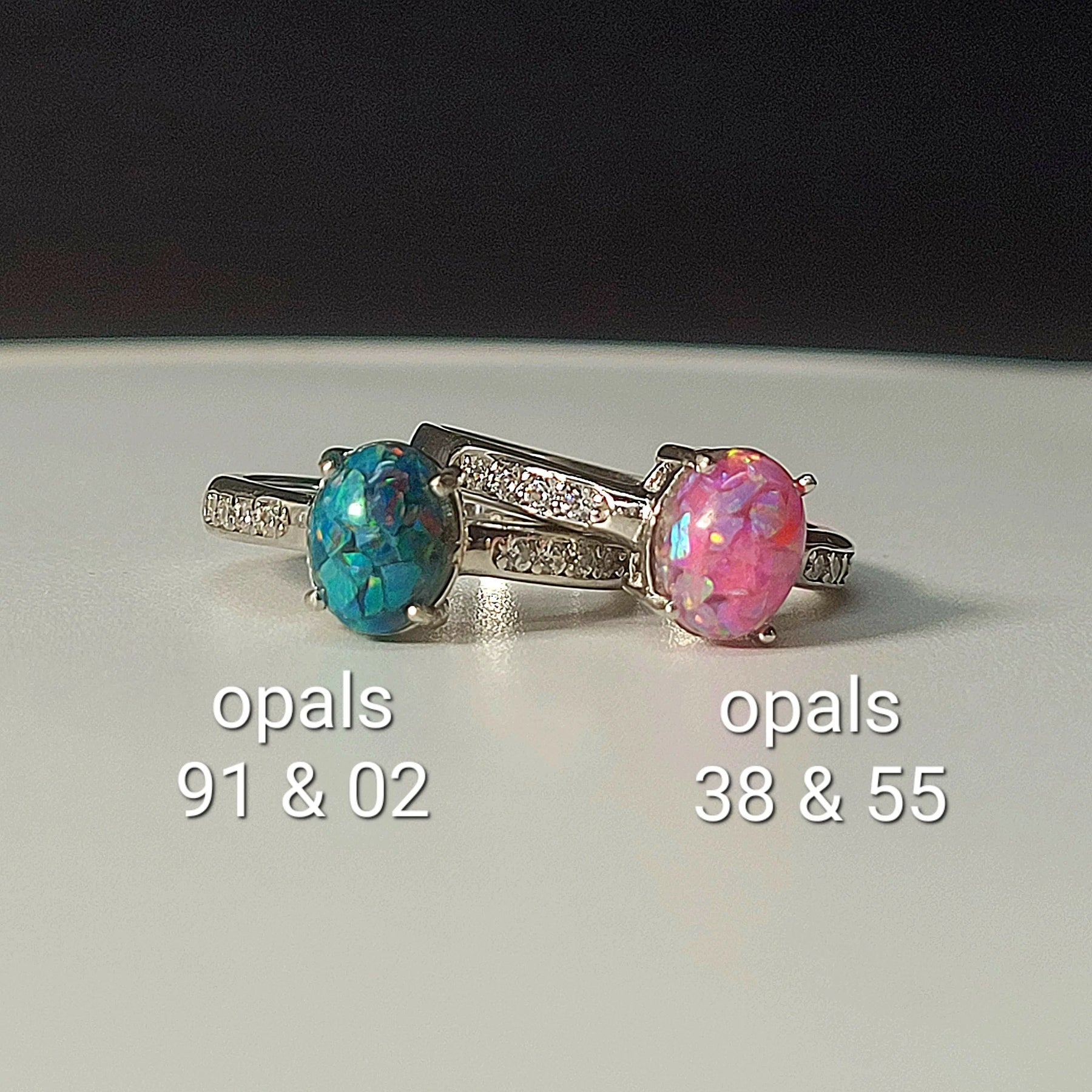 Two sterling silver opal rings: one blue/green, the other pink. Bands have cubic zirconia accents. Memorial jewelry for ashes or keepsakes.